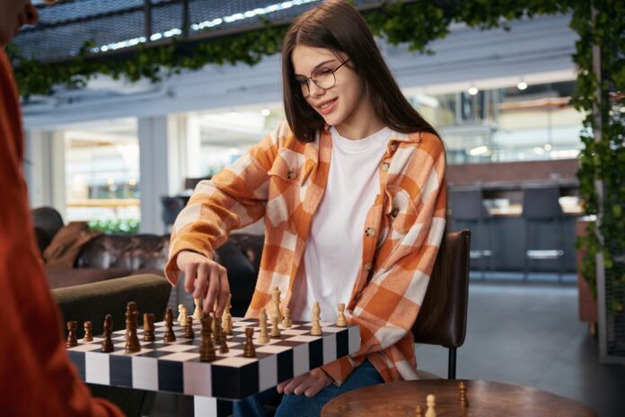 Cute girl playing chess in modern studio